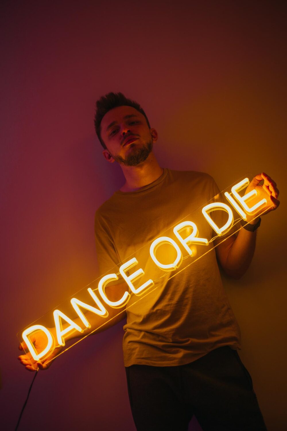 Парень, держащий желтую неоновую надпись "Dance or die" 3